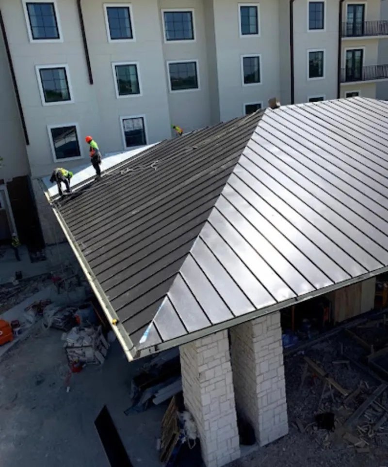 Crew installing standing seam metal roof panels on a commercial project in Beaumont